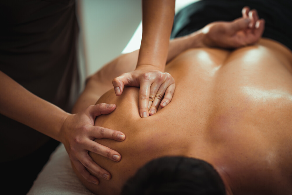 A therapist massaging a male client’s shoulder
